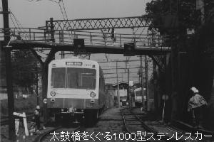 太鼓橋をくぐる1000型ステンレスカー
 狐ヶ崎ヤングランド前駅の西側にあった跨線橋は通称「太鼓橋」と呼ばれていました。最近、耐震構造の橋として生まれ変わりました。